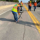 Construction crew using the GMP 025-C dispensing system to fill expansion joint cracks during bridge deck repair.