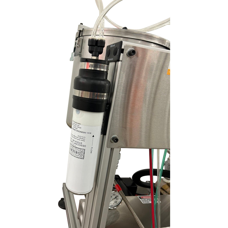 Close-up of the AST GMP 025 dispensing system, showing a mounted white filtration canister connected to stainless steel tanks with clear tubing.